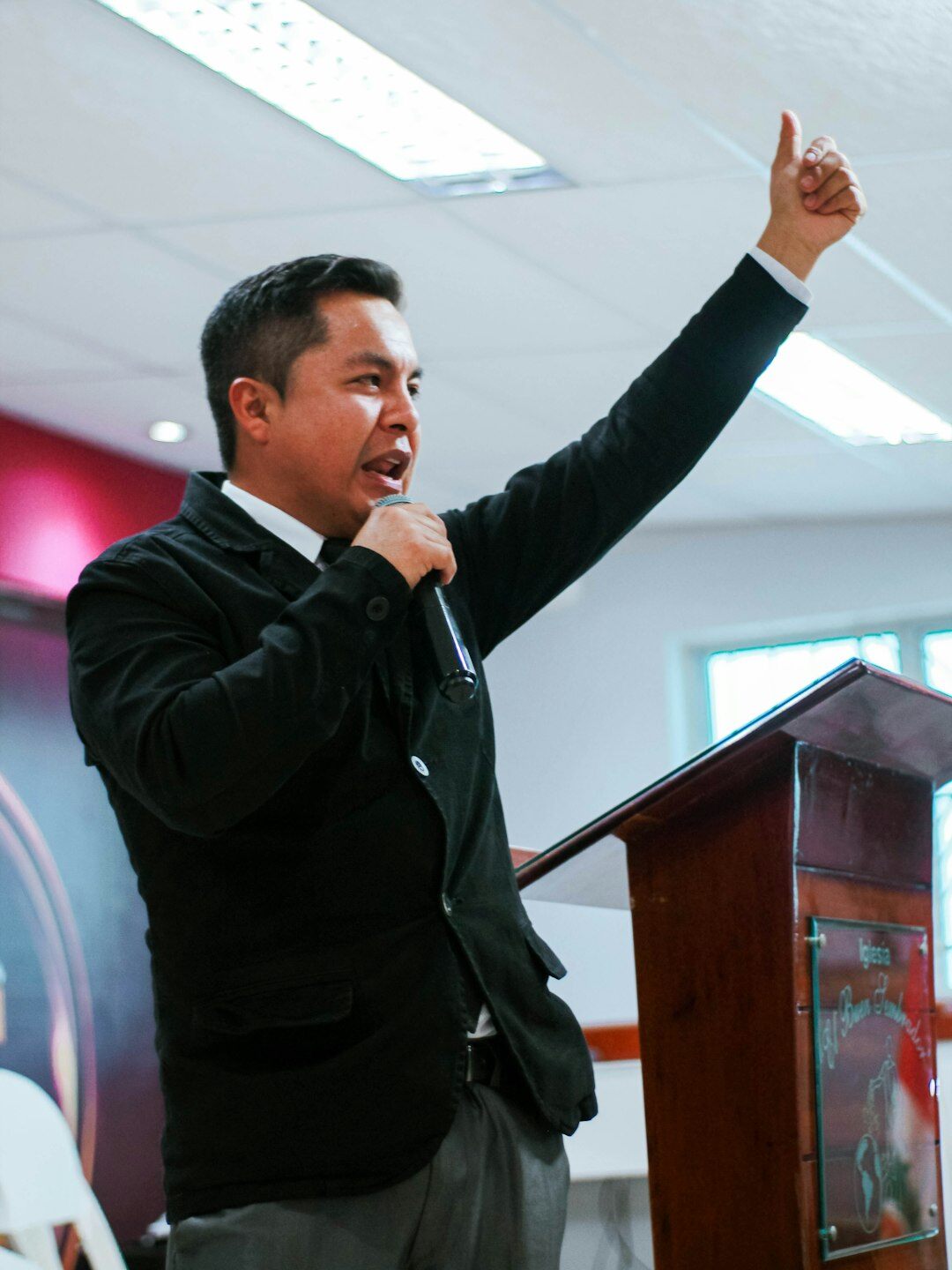 Confident Brazilian man speaking in front of a small audience in a bright room