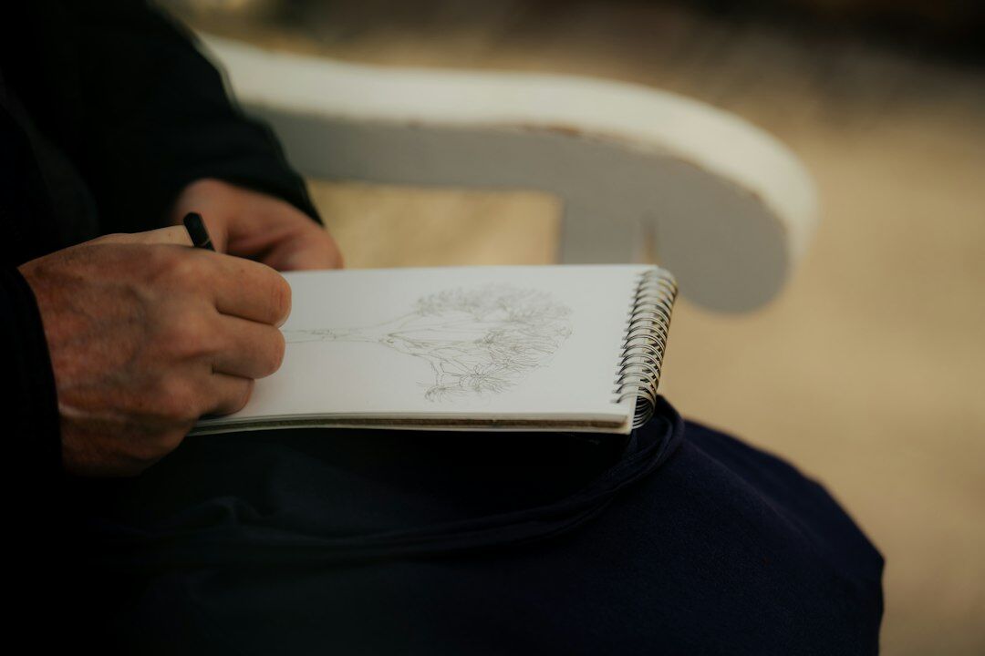 Close up of a person writing notes in a notebook during a personal development session