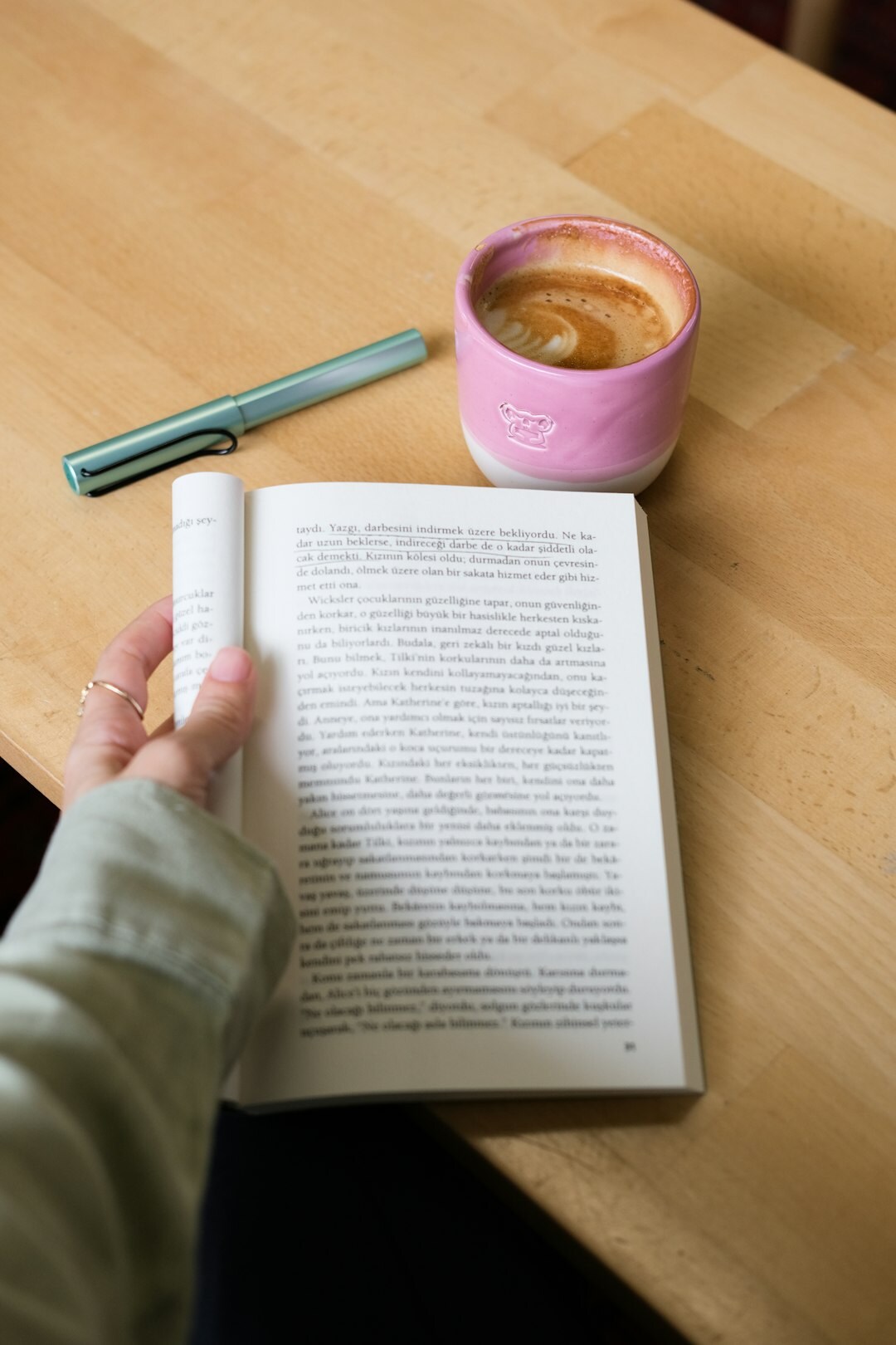 Open journal and pen on a wooden table with a cup of coffee